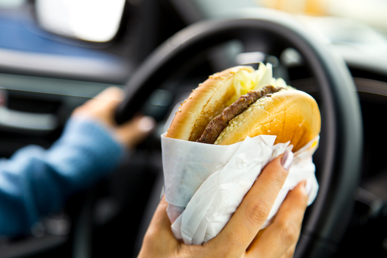 Woman holding a burger while driving