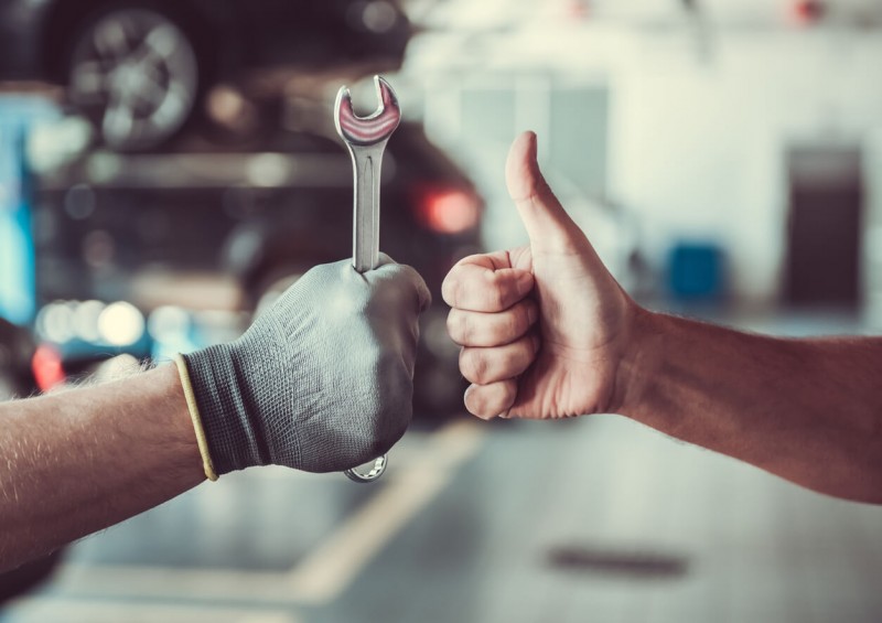 A mechanic holding a spanner and thumbs up