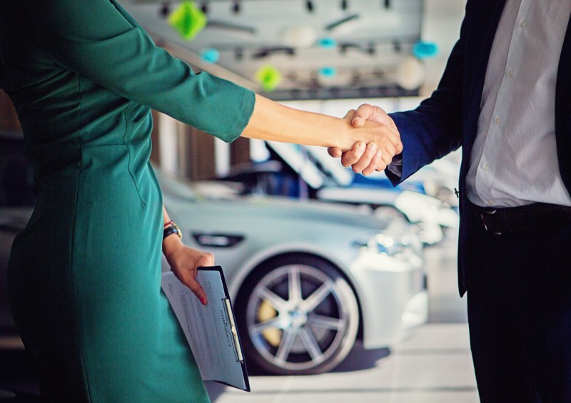 Car dealer and customer shaking hands over a car deal