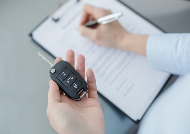Customer holding car key and signing contract Customer holding car key and signing contract