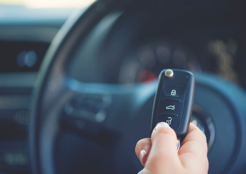 Person holding car keys in front of steering wheel